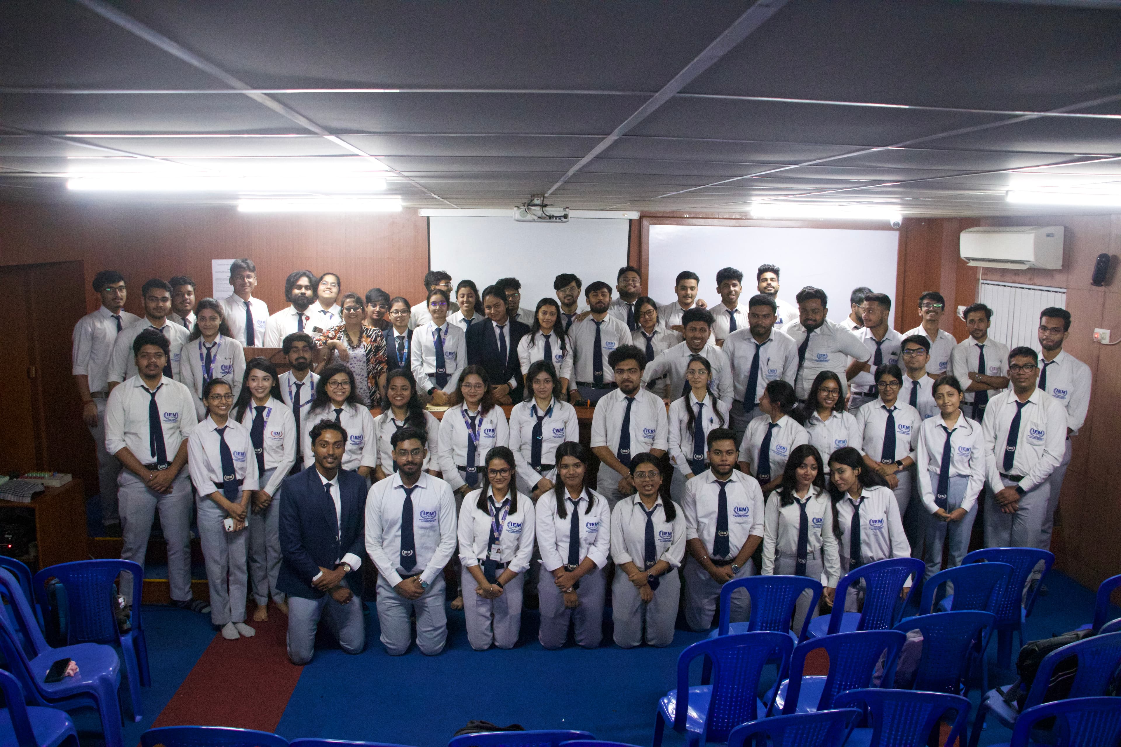 Group of students in formal attire standing together outside an institutional building
